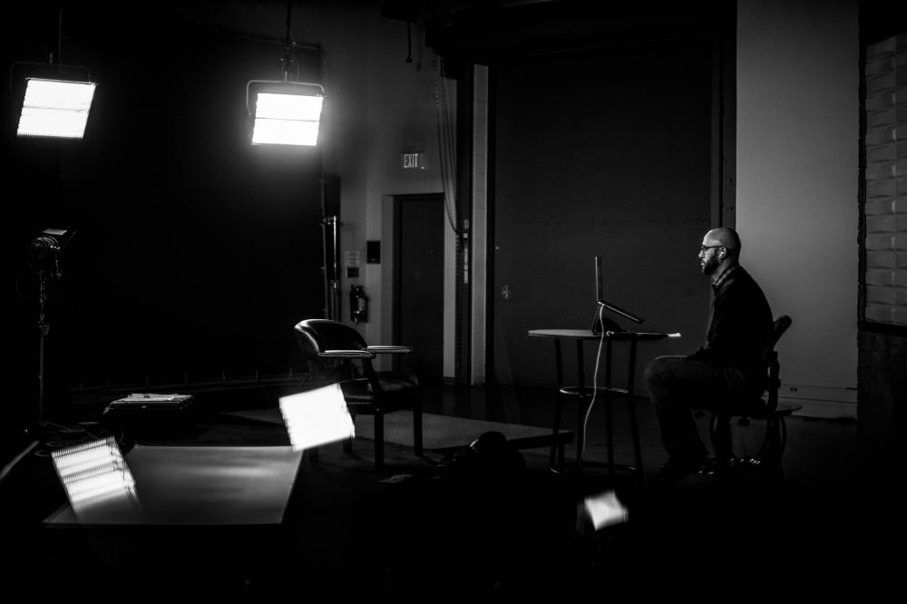 man sitting in studio, with studio lights on, giving a virtual presentation while seated